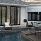 Luxury backyard patio and pool area featuring large black-frame sliding glass doors and matching windows on a modern white house.