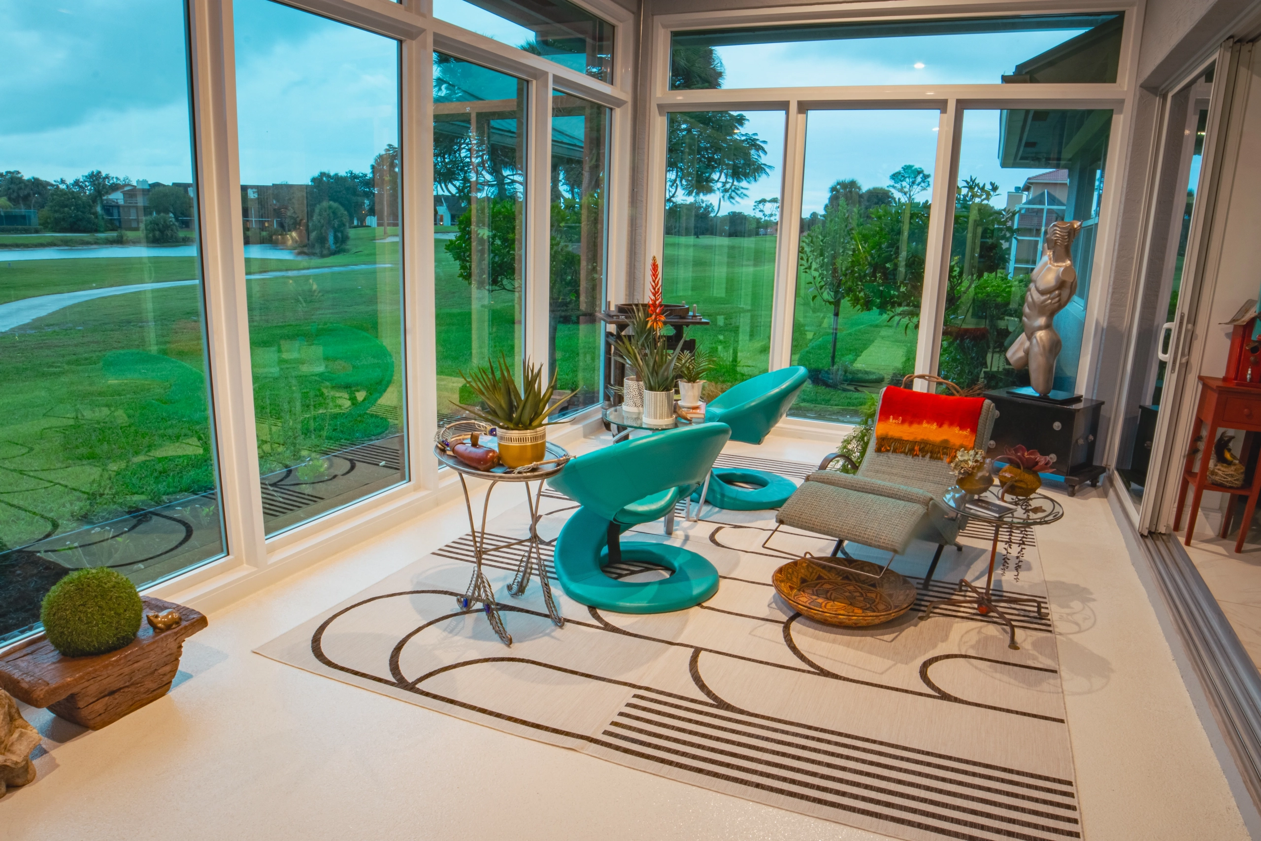Modern sunroom featuring floor-to-ceiling Quality Windows and Doors overlooking a lush green golf course.